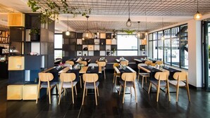 Un restaurante moderno con techo de diseño en cuadrícula, mesas y sillas de madera.