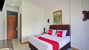 A hotel room with a large bed, a wooden headboard, a painting on the wall, and a telephone on the nightstand.