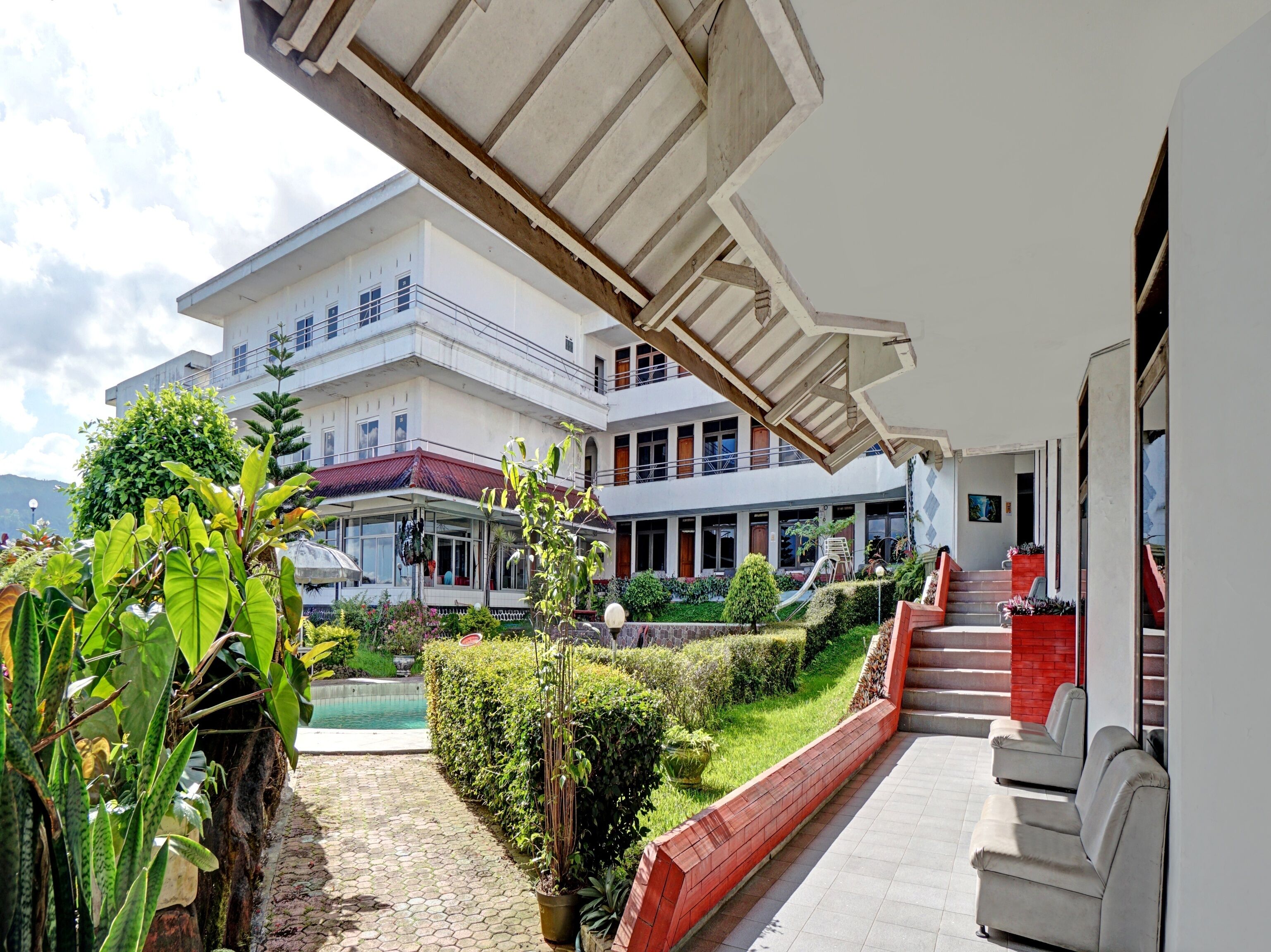 A multi-story building with a covered outdoor area, a swimming pool, and a staircase leading to the upper floors.