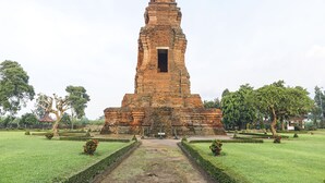 A large, ancient brick structure with a central doorway, surrounded by well-maintained gardens and trees. - Hotel O Desa Wisata Kampung Majapahit (Bejijong)