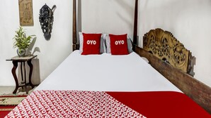 A bed with a wooden headboard, two red pillows with the word "OYO" on them, a white bedspread, and a red and white patterned blanket. - Hotel O Desa Wisata Kampung Majapahit (Bejijong)