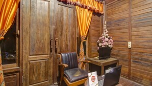 A wooden room with a desk, two chairs, a laptop, and a vase of flowers. - Hotel O Desa Wisata Kampung Majapahit (Bejijong)