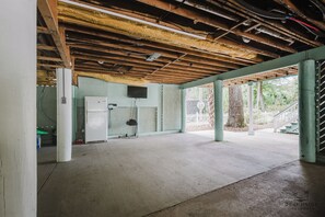 Une pièce vide avec un sol en béton, un réfrigérateur blanc et un téléviseur fixé au mur.