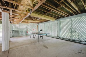 Une pièce avec une table de ping-pong, un hamac et un plafond avec des poutres apparentes.