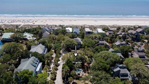 An aerial view of a coastal residential area with houses, a beach, and a swimming pool.