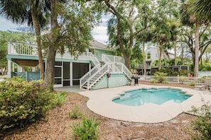 A pool area with a covered deck, a staircase, and a fenced garden.