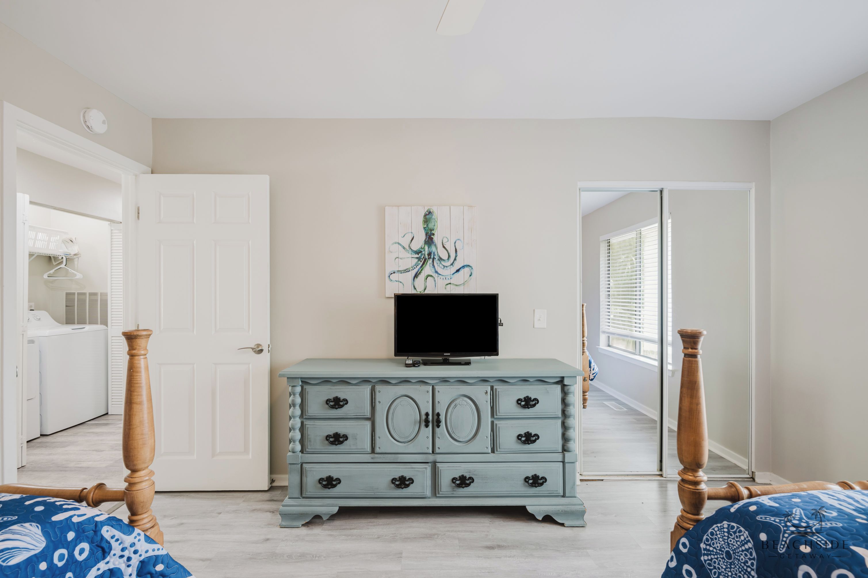 A bedroom with a dresser, a television, and a painting on the wall.