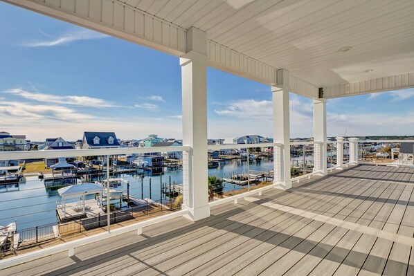 Une terrasse couverte offrant une vue sur un port de plaisance et des maisons.