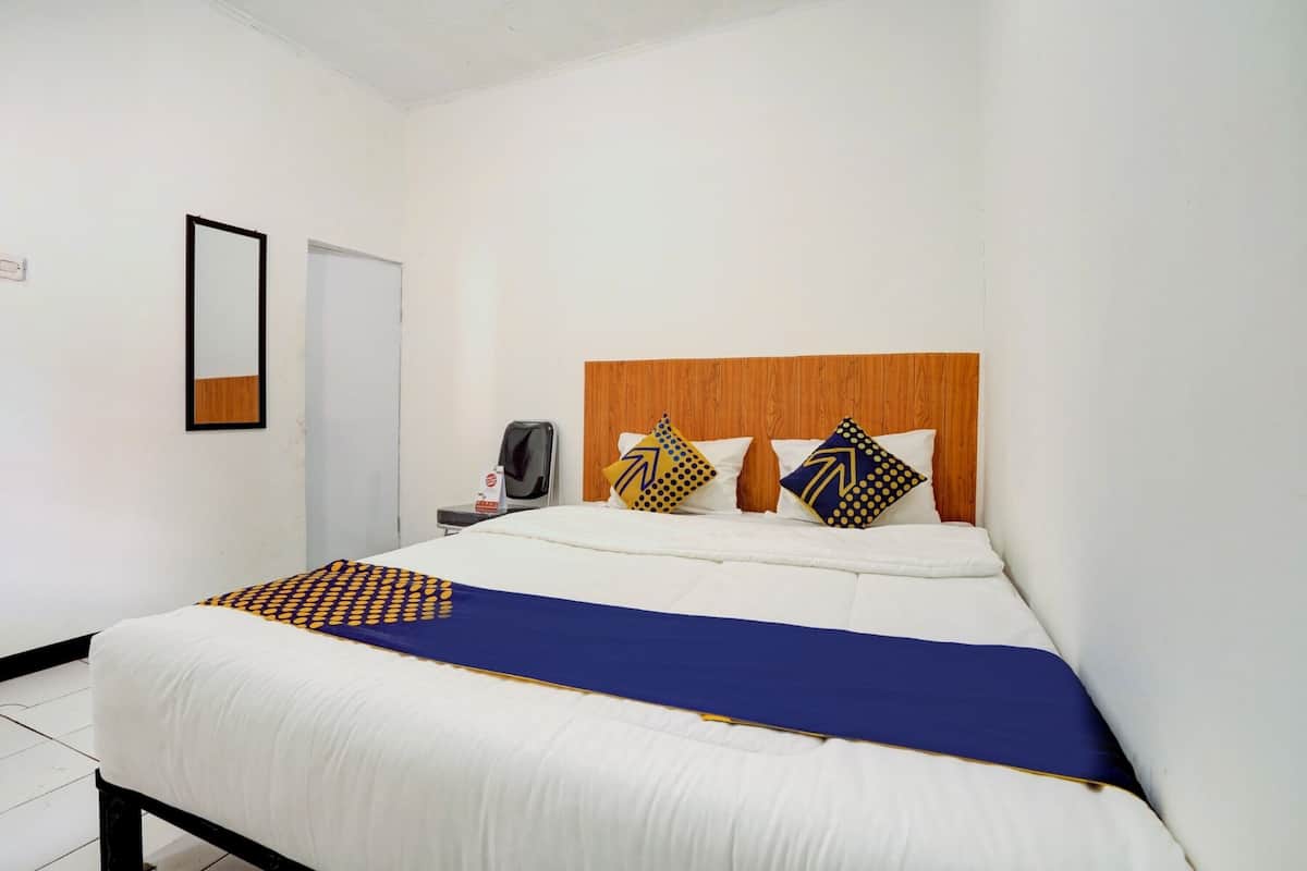Une chambre d’hôtel avec un lit, une tête de lit en bois et une table de chevet avec une lampe.