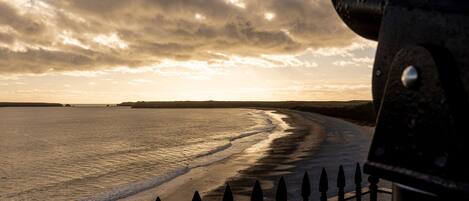 Une scène de plage avec une clôture et un ciel nuageux.