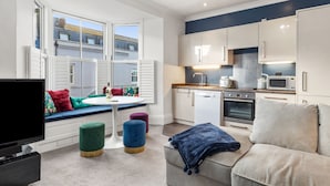 A modern apartment with a kitchen, dining area, and living room. - Caldey Bay Apartment - Lovely Sea Views (Tenby)