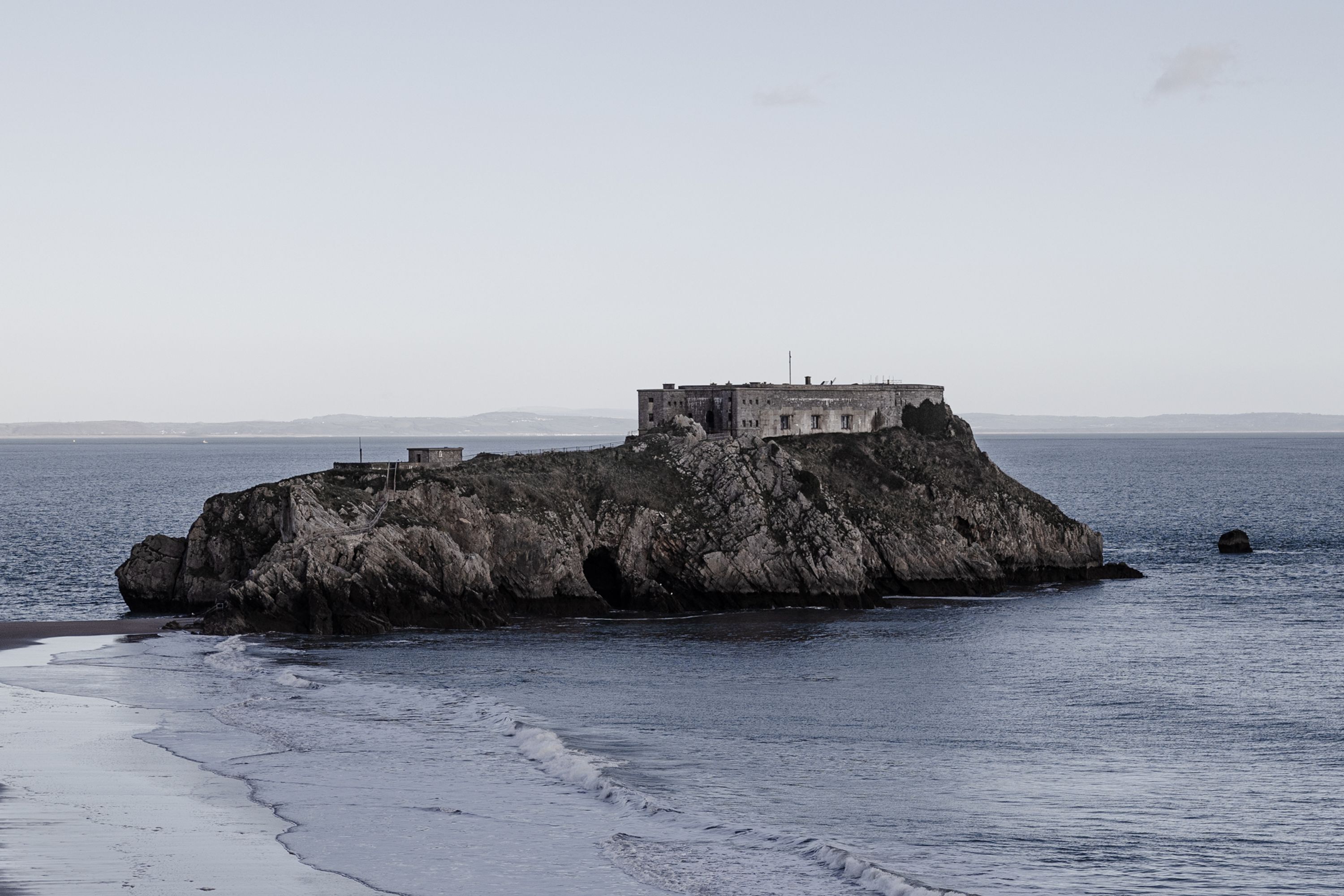 A coastal building on a rocky outcrop with a view of the sea.