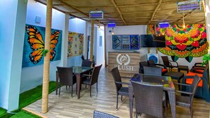 An indoor seating area with tables and chairs, a ceiling with hanging lights, and walls adorned with colorful artwork. - PLUSH HOTEL (Abuja)