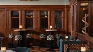 Un rincón de bar acogedor con paneles de madera, taburetes estampados y una escalera de caracol.