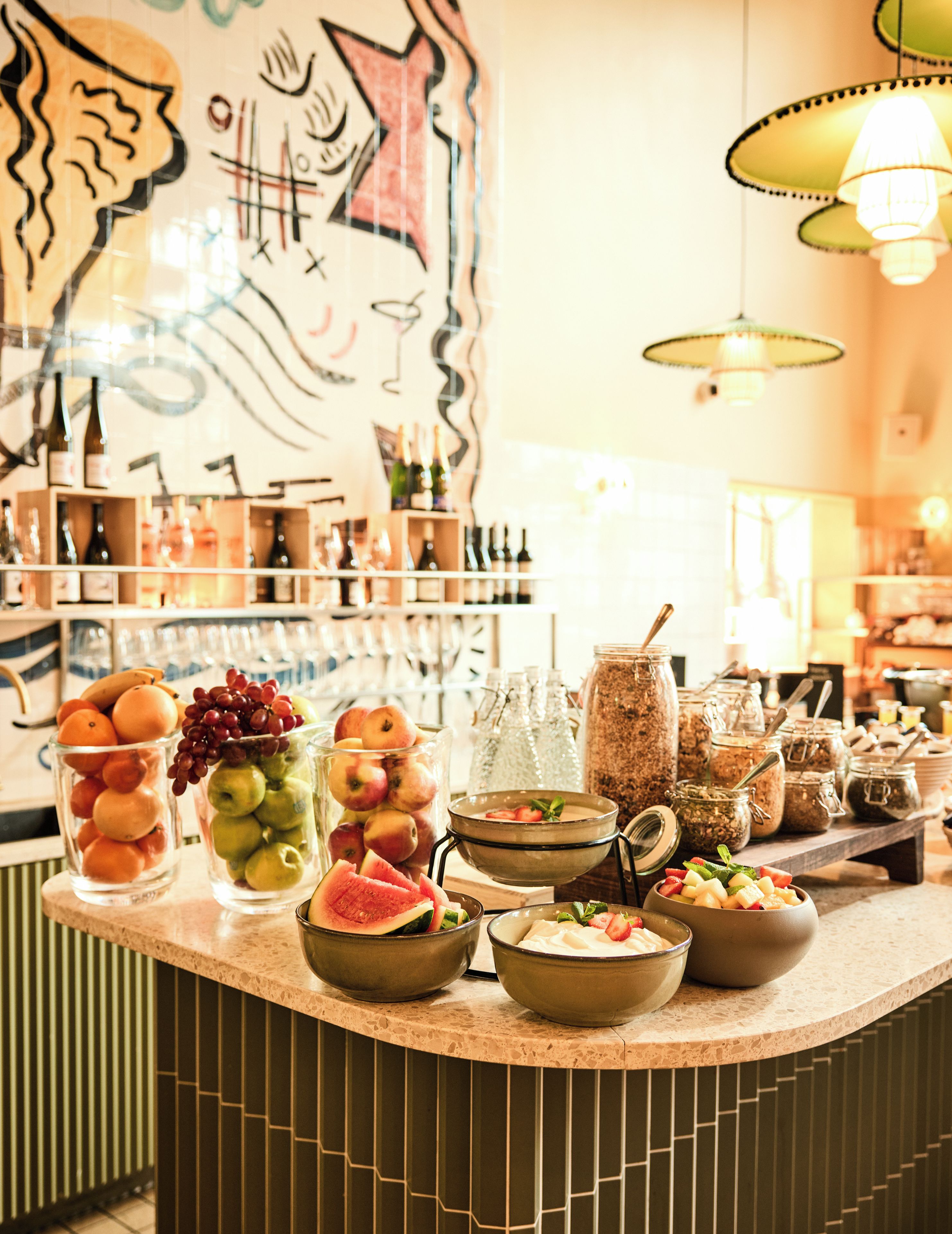 A bar area with various food and drink items, including fruits, bottles, and jars.