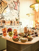 Una zona de bar con diferentes alimentos y bebidas, entre ellos frutas, botellas y frascos.