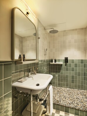 A modern bathroom with a white sink, mirror, and shower.