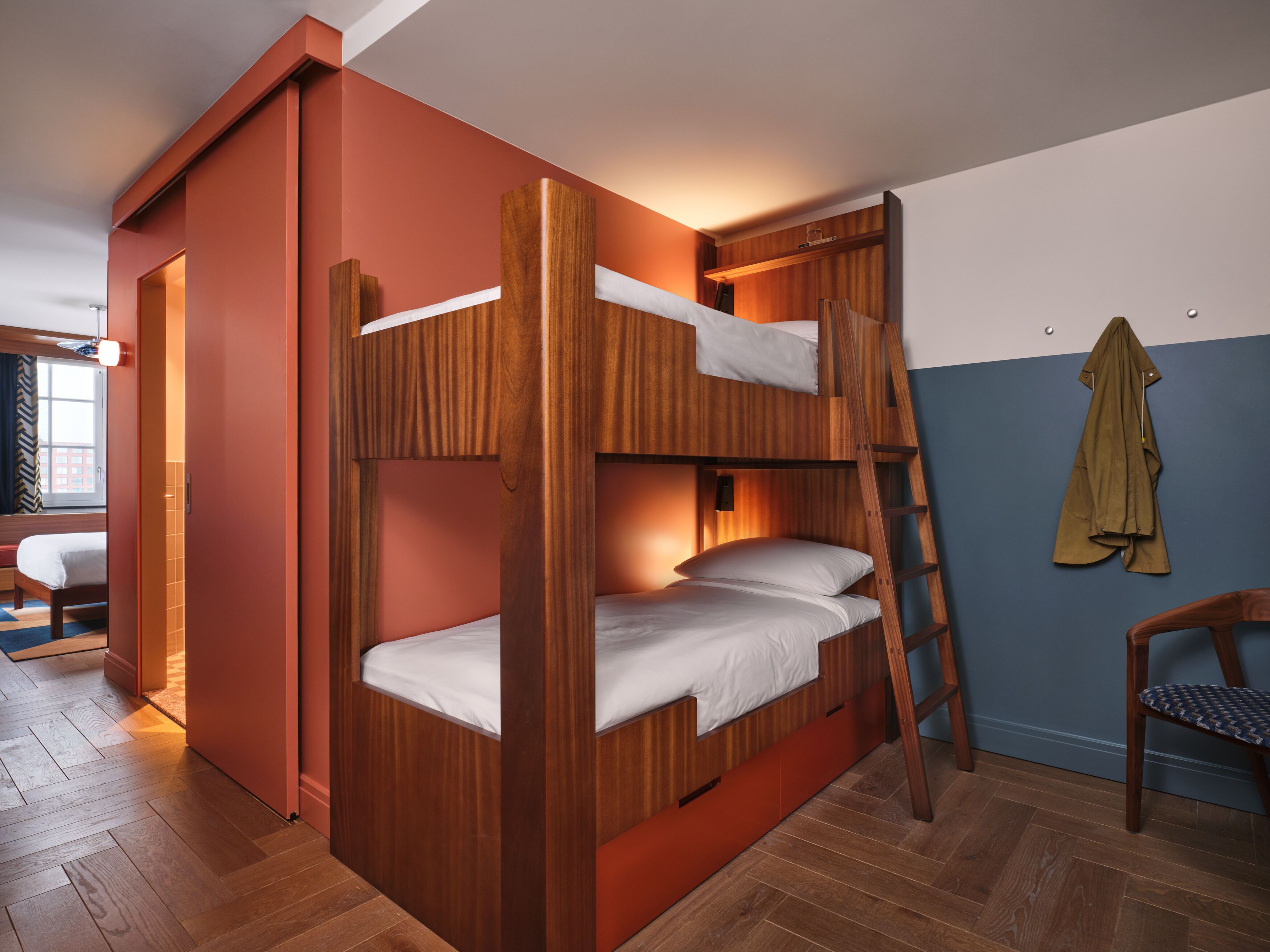 A bunk bed with a ladder, wooden walls, and a window with curtains.