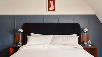A neatly made bed with white linens, a dark headboard, and two bedside lamps on wooden nightstands.