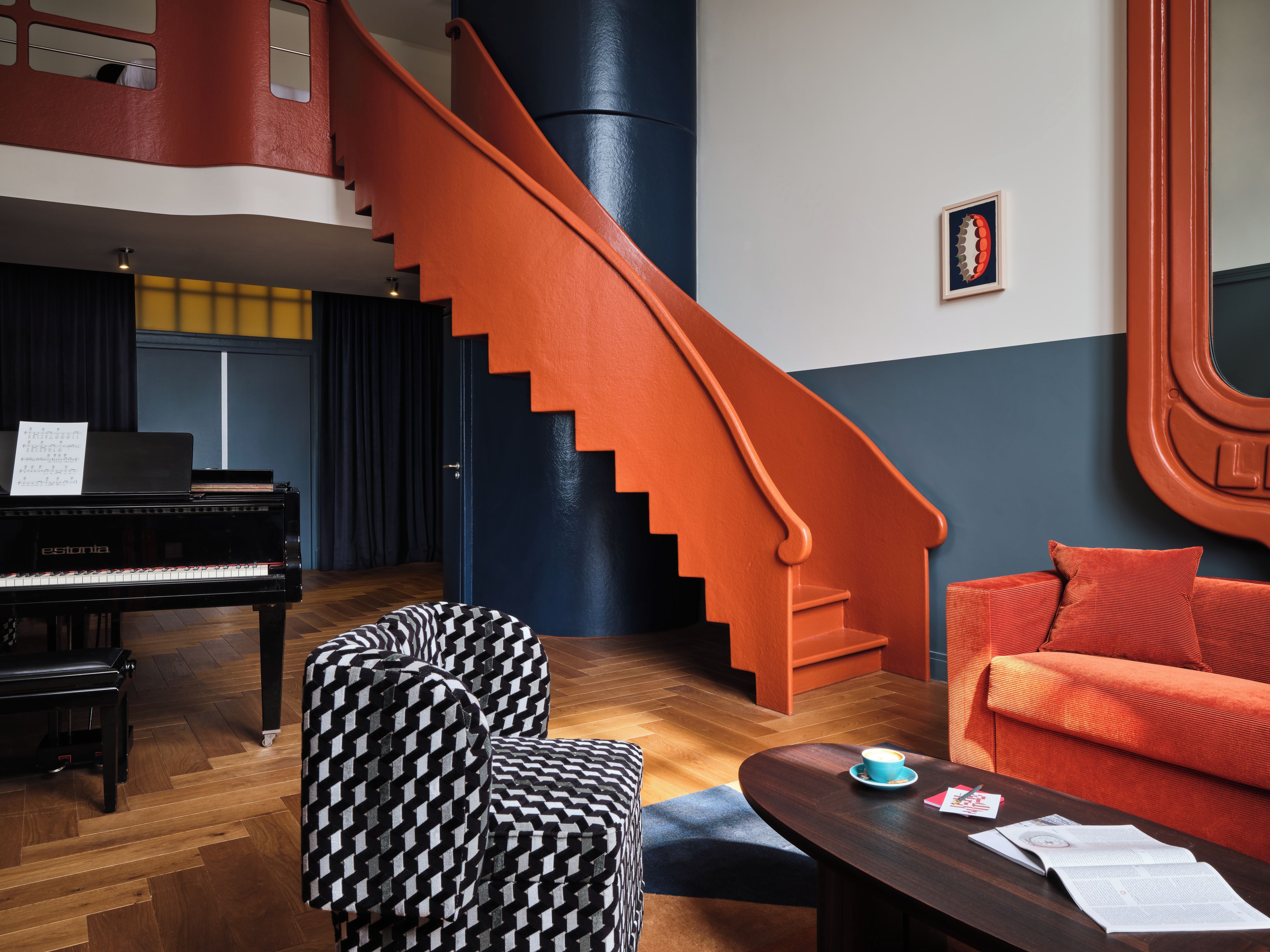 Una habitación con un piano, una escalera, un sofá y una mesa de centro.