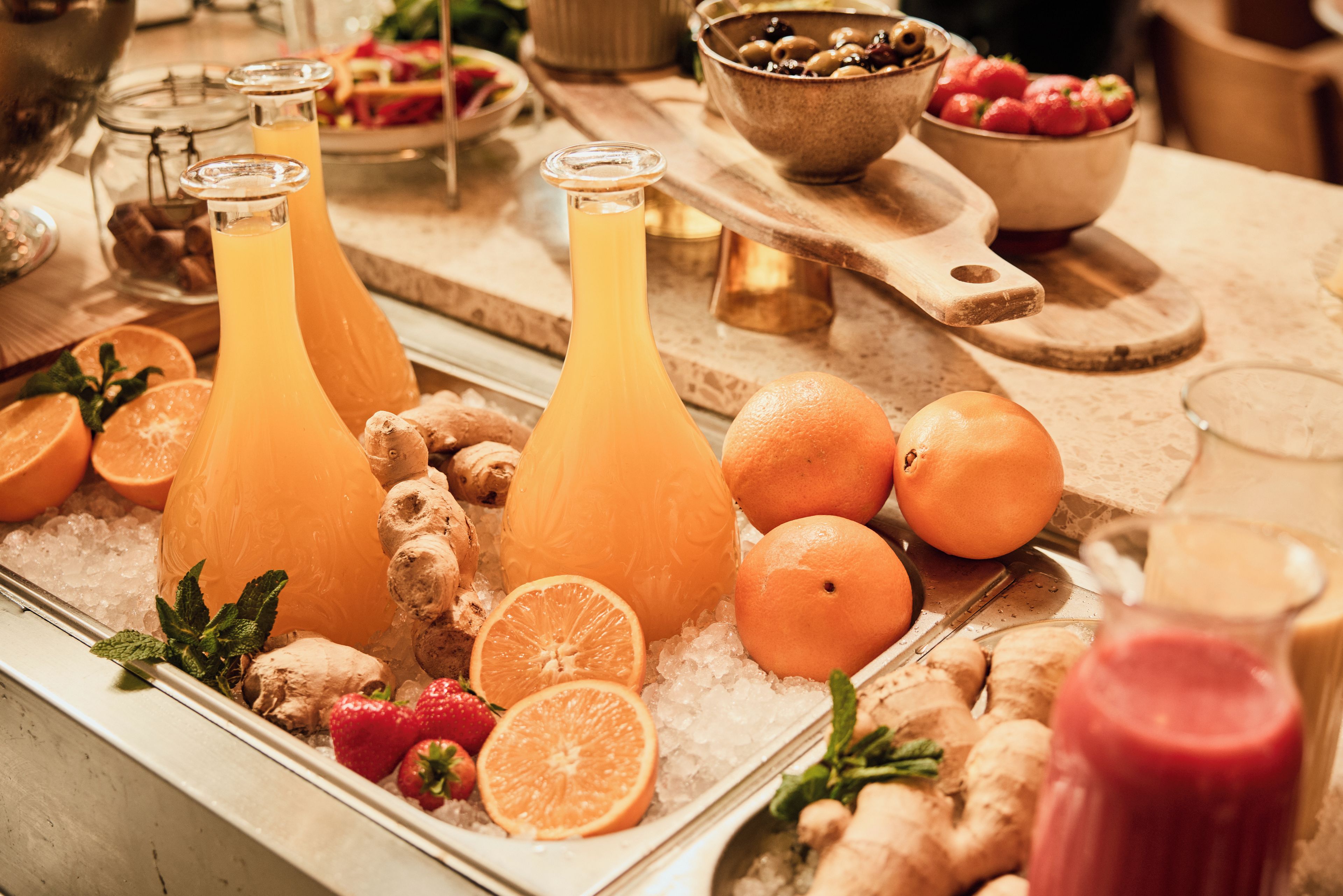 A beverage station with various drinks, fruits, and ice.