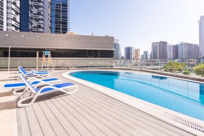 Una piscina al aire libre, sillones reclinables de piscina