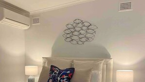 Ein ordentlich bezogenes Bett mit zwei Kissen, einer Wanddekoration und zwei Nachttischlampen.
