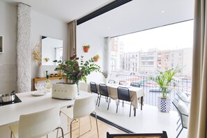 Un espace de restauration moderne, doté d’une grande table, de chaises et offrant une vue sur la ville grâce à de larges fenêtres.