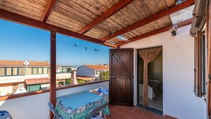 Ein Balkon mit Tisch und Stühlen, einer Holzbalkendecke und Blick auf Gebäude.