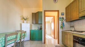 Eine kleine Küche mit Esstisch, Stühlen, einem Kühlschrank und Holzausbau.