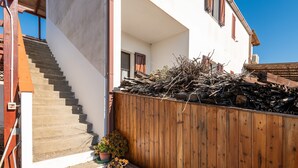 Eine Treppe führt zu einem weißen Gebäude mit Holzzaun und Blumentöpfen.