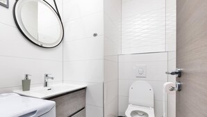 A modern bathroom with a white sink, mirror, and toilet. - Apartment First Mary (Matulji)