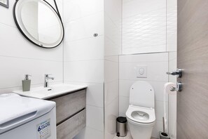 A modern bathroom with a white sink, mirror, and toilet. - Apartment First Mary (Matulji)