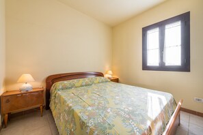 Une chambre à coucher avec un lit, des lampes de chevet, une fenêtre et une table de chevet.