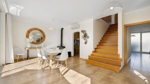 Un vaste espace de vie agrémenté d’un escalier en bois, d’une table à manger avec des chaises et d’un grand miroir mural.