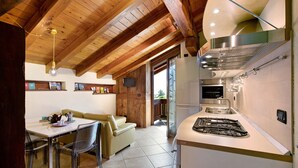 Une cuisine équipée d’une cuisinière, d’un évier et de poutres en bois au plafond.