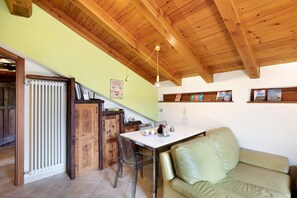 Ein Essbereich mit Tisch, Stühlen, einer Heizung, Holzschränken und einer Couch.