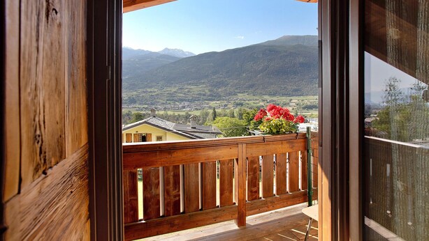 Un balcon en bois offrant une vue sur un paysage montagneux.