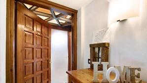Une porte en bois ornée d’un motif quadrillé, un comptoir en bois sur lequel le mot « HOME » est inscrit en lettres, et un luminaire fixé au mur.