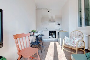 A compact living space with a dining table, chairs, a sofa, a television, and a kitchen area.