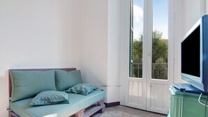Ein Zimmer mit einem Bett auf Holzbalken, einem Fernseher auf einem Tisch und einer Tür, die nach draußen führt.