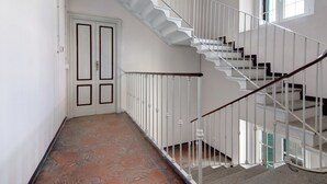 Eine Treppe mit weißen Geländern und einem hölzernen Handlauf, der zu einer Zwischenebene mit einer Tür führt.