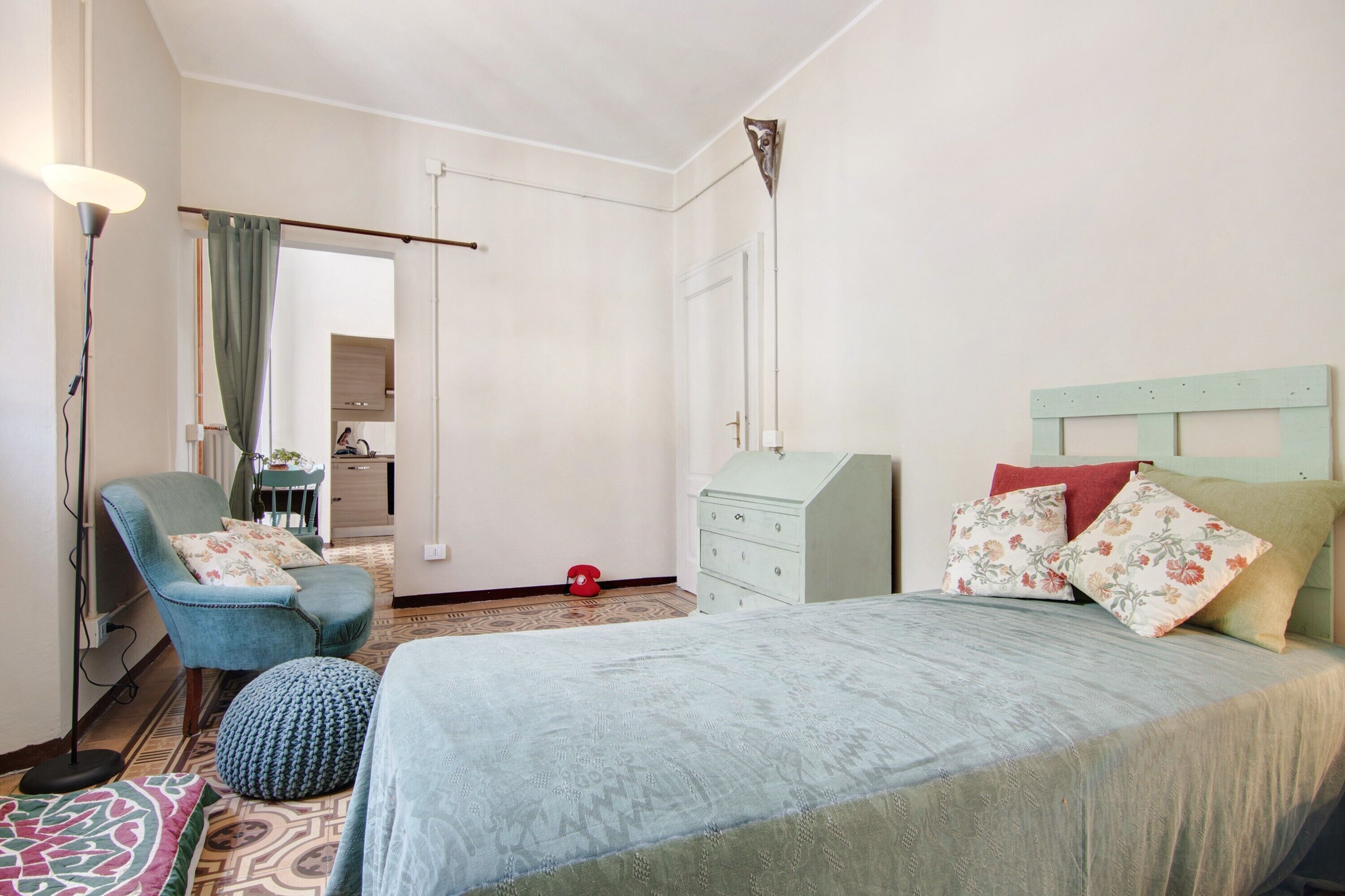 A bedroom with a bed, a chair, a dresser, and a mirror.