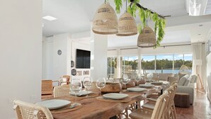 A dining area with a wooden table set for six, surrounded by wicker chairs.