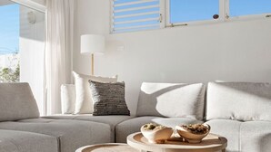 A modern living room with a grey sofa, a round wooden coffee table, and a white lamp.