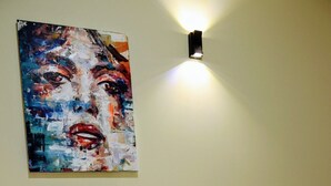 Une chambre d’hôtel avec un lit, un tableau au mur, une bouteille de champagne et un panier de fruits.
