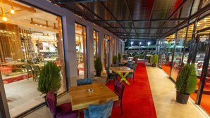 Un espace de restauration intérieur avec des tables et des chaises, de grandes fenêtres et une moquette rouge.