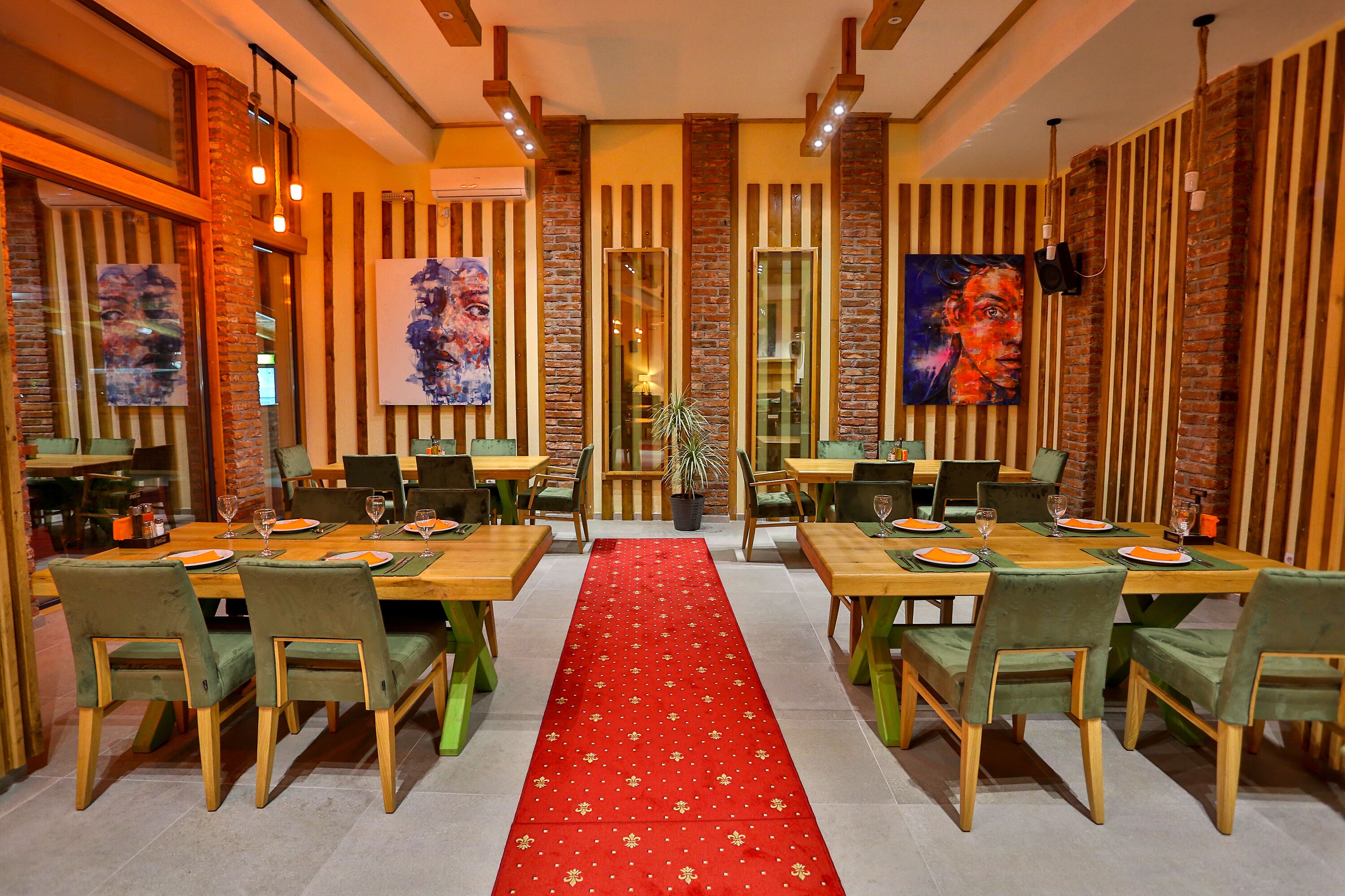 Ein Restaurant mit Holztischen und -stühlen, einem roten Teppich und Kunstwerken an den Wänden.