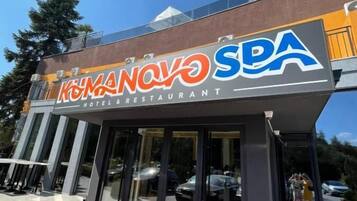 A hotel and restaurant with a red carpet entrance, glass doors, and a clear sky.