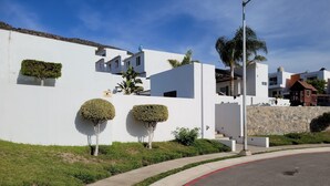 Un bâtiment moderne aux murs blancs, avec un mur en pierre et un bordure de trottoir rouge.